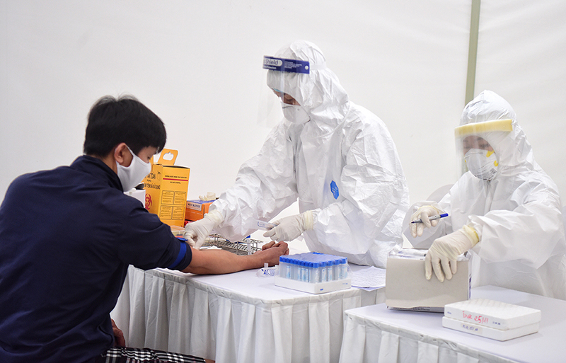 Nhân viên y tế thực hiện lấy mẫu máu xét nghiệm Covid-19 cho bệnh nhân