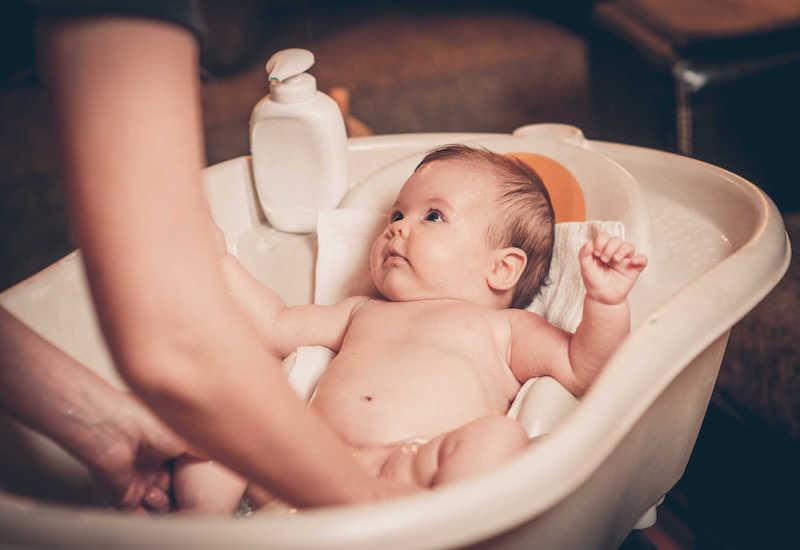 Lau người bé bằng nước ấm để giảm nhiệt bớt kết hợp tắm rửa hàng ngày để da luôn sạch sẽ và khô thoáng