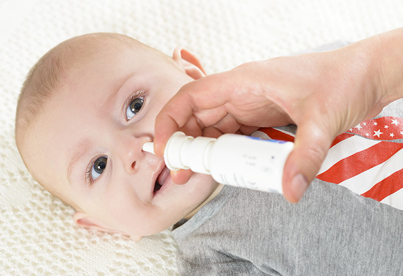 Bố mẹ có thể xịt rửa mũi cho bé bằng nước muối sinh lý được mua ở quầy thuốc