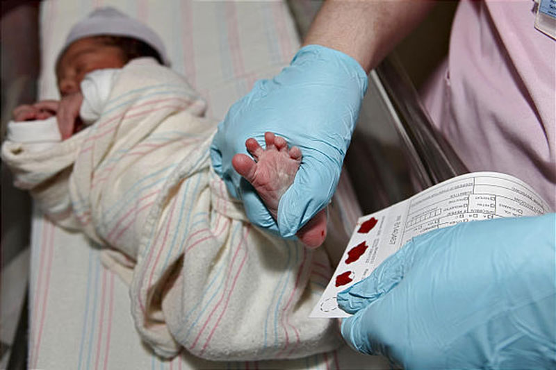 Nhân viên y tế lấy máu gót chân để sàng lọc sơ sinh cho trẻ