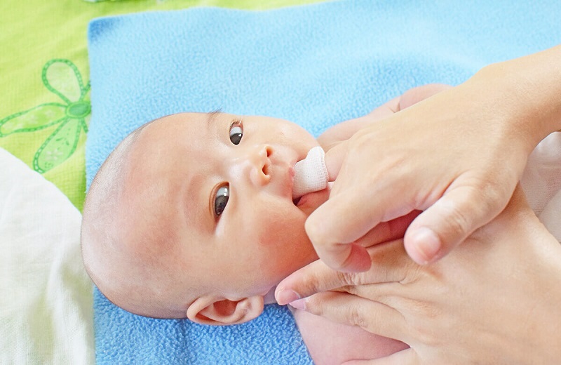 Bố mẹ nên làm sạch lưỡi cho bé bằng khăn sạch và nước ấm