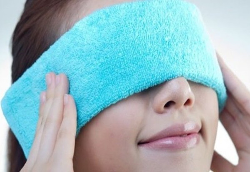 Chườm ấm vùng mắt bằng khăn sạch để giảm đau