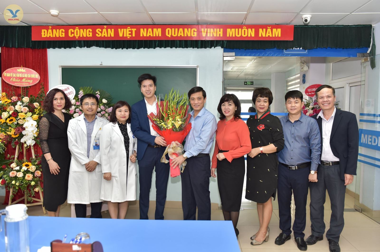ThS. Nguyễn Trí Anh - Tổng GIám đốc MED GROUP (thứ 4 từ trái qua phải) nhận bó hoa tươi thắm chúc mừng Ngày 27-2 của đại diện Quận ủy Ba Đình.
