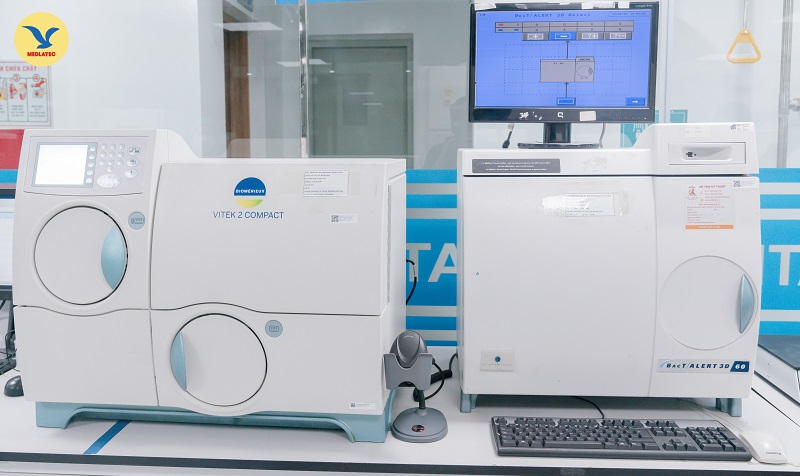 Máy định danh nhanh và kháng sinh đồ tự động Vitek 2 compact (bên trái) với máy cấy máu (bên phải) hiện đại, tự động hoàn toàn tại Trung tâm Xét nghiệm MEDLATEC