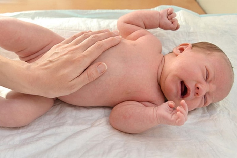 What are the common causes of a stiff stomach in newborn babies?
